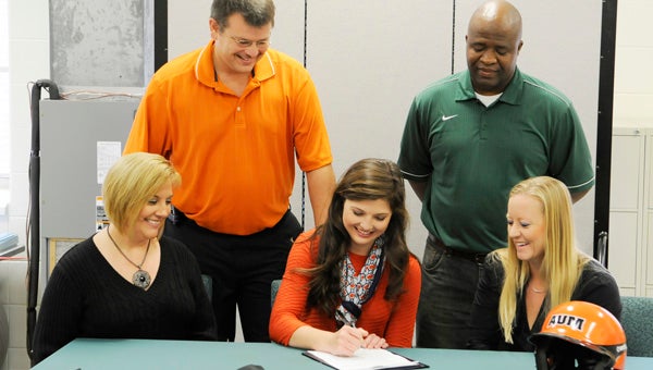 Dallas County High School’s Amy Persinger, middle, signs her letter of intent to sign with Auburn Montgomery.  Persinger’s parents, Kim and Robbie, left, and new head coach, Chris Wilcoxson,  right, and current softball coach Willie Moore, standing right, look on. 