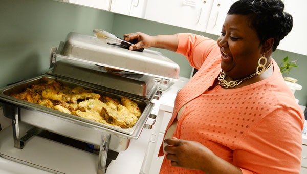 Sabrina Walker uncovers a tray of baked chicken before she spoke during Tueday’s Sensational Selma Cooks African American event at the Selma-Dallas County Library.  Walker’s demonstration drew a large crowd to the library. (Jay Sowers | Times-Journal)