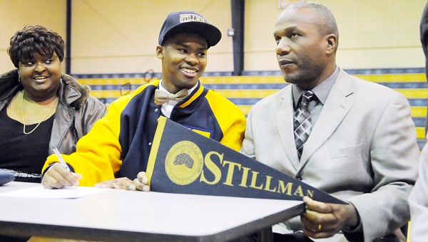 Keith High School’s Maurice Crumpton talks with head coach Harry Crum as he signs the paperwork to complete his letter of intent. Crumpton will play football at Stillman College next season.