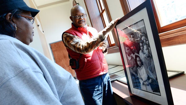 Alvin Peters, center, holds up a historic photograph for his cousin Tamara Thomas to look at Tuesday at the Selma Interpretive Center.  The center is hosting a display of historic civil rights photographs daily through April 4. (Jay Sowers | Times-Journal)