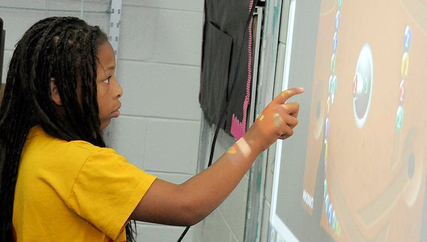 Iyana Woods, a fifth grade student at Cedar Park Elementary, plays a math game on the smart board Tuesday during the summer enrichment program Tuesday. (Sarah Robinson | Times-Journal)