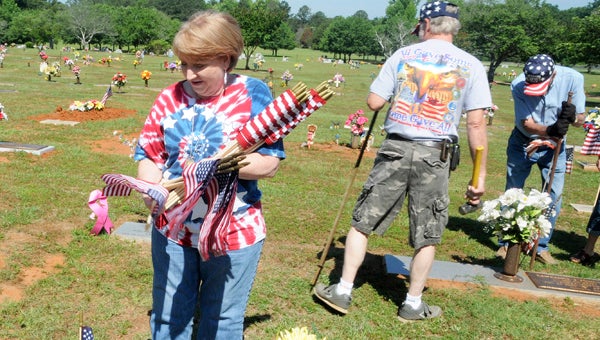 Patsy Stone places a flag beside the grave of a serviceman at the Pineview Memorial Gardens in Valley Grande. 