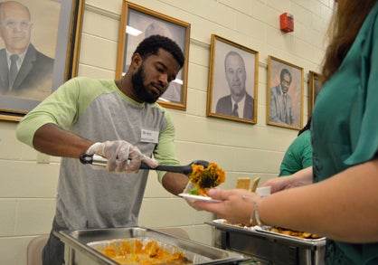 Volunteer Khalil Jordan serves sweet potatoes during Habitat for Humanity's annual Food Fest and Auction on Thursday.