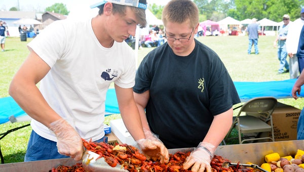 Patrick Haskell, left, and Tyler Duncan, right, work together to scoop a load of crawfish to serve during the Central Alabama Crawfish Festival, which was held Saturday at Lions Fair Park. 