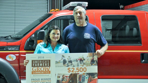 Wendy Yeager presents Orrville Volunteer Fire Department Chief Bill Grimes a $2,500 donation from the Monsanto Fund to use toward equipment. 
