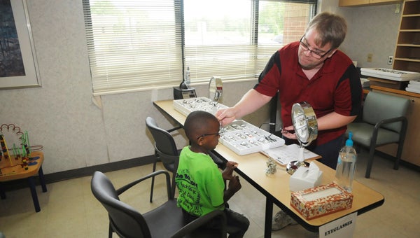 LensCrafters One Sight volunteer Larry Crockett helps Rakeim Mitchell pick new glasses at the 12th Annual Black Belt Eye Clinic Wednesday in Marion. 