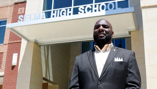 New Selma football coach Keon Handley poses for a photo in front of the school Friday afternoon.  Handley met the team for the first time later Friday afternoon and then made the trip to Montgomery to see the Saints in action in their spring game against Robert E. Lee. --Daniel Evans