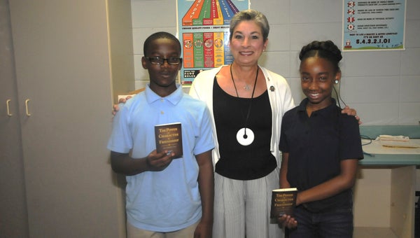 Payne Elementary School students Roosevelt Merchant (left) and Shaniya Blanks (right) are pictured with Selma Rotary Club President Manera Searcy at a book giveaway Friday.