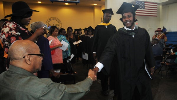 Selma University graduate Ahmad Jackson shakes his grandfather’s hand, the Rev. Arthur Jackson Jr., as commencement concludes. 