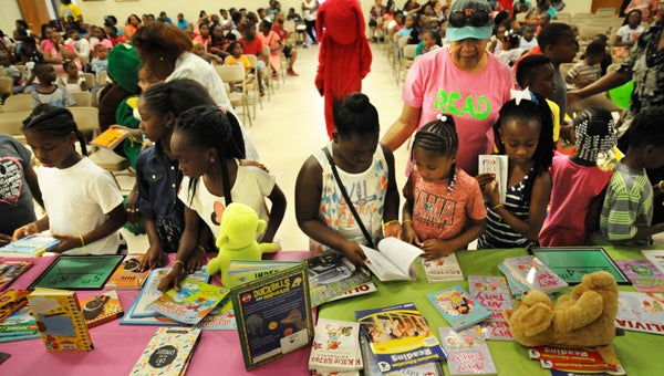 Children line up to pick out a book to take home during the Reading is Fun week kickoff at the Carl C. Morgan Convention Center on Monday.