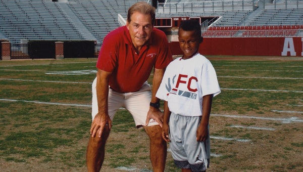 Eight-year-old Omari Smith stands with University of Alabama head coach Nick Saban at the 2016 Nick Saban Football Camp. 