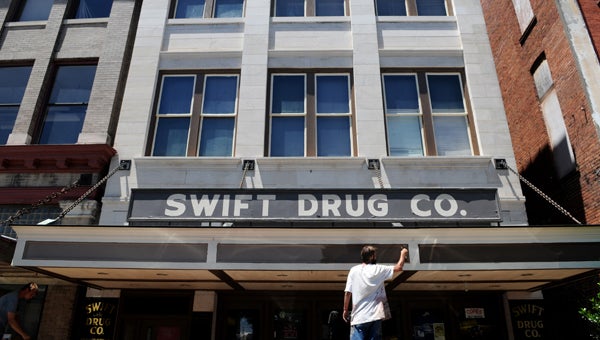 Steven Neeley paints the exterior of Swift Drug Co. on Broad Street. The drug store is getting prepared to celebrate 100 years of business in October.