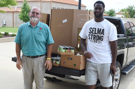 Jeff Harrison of the Selma Area Food Bank poses for a photo with NFL defensive end Michael Johnson at Johnson’s Family Fun Day Saturday at Wallace Community College.  Admission to the event was a perishable food item.  For more see sports on page 8A.  --Daniel Evans