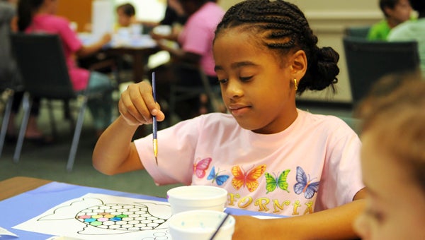 Kylie Wideman, 7, paints a fish using watercolors at the Selma-Dallas County Library Monday morning.  --Emily Enfinger