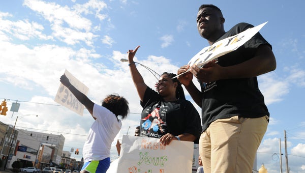 A Selma Center for Nonviolence, Truth and Reconciliation executive director Ainka Jackson (center) stands with Amber Strong (left) and Oluwadamilola Animushaun (right) at the foot of the Edmund Pettus Bridge on Friday during a Stop the Violence rally.
