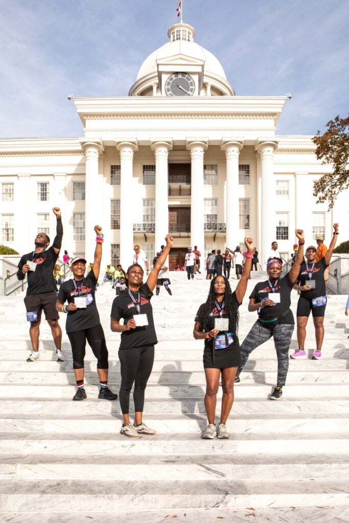Photo Courtesy of Janelle Gonzalez. Team Sole Journey of New York stands at the Alabama State Capitol to finish the Selma to Montgomery race” From left to right: Steven Forbes, Lenora Mariner, Andrea Haritos, Regina “the Queen” Fleming, Sharon Marine, Yolanda Jefferson.